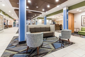 A lobby with a sofa, two armchairs, a patterned rug, and a reception desk. - Holiday Inn Express Villa Rica by IHG (Villa Rica)