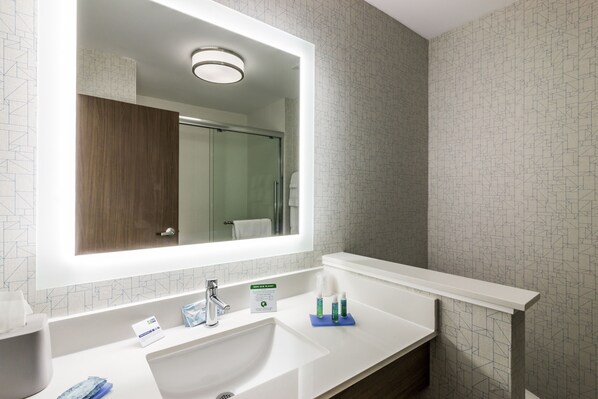 A modern bathroom with a large mirror, white sink, and a towel rack.