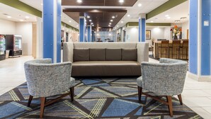 A lobby with a sofa and two armchairs, a reception desk, and vending machines. - Holiday Inn Express Villa Rica by IHG (Villa Rica)