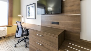 A modern office space with a wooden desk, a black office chair, a flat-screen TV mounted on the wall, and a framed picture. - Holiday Inn Express Villa Rica by IHG (Villa Rica)