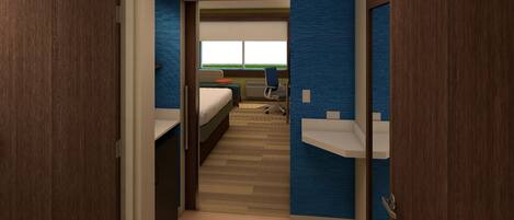 A hotel room with a bed, a desk, a chair, and a view of a green landscape.