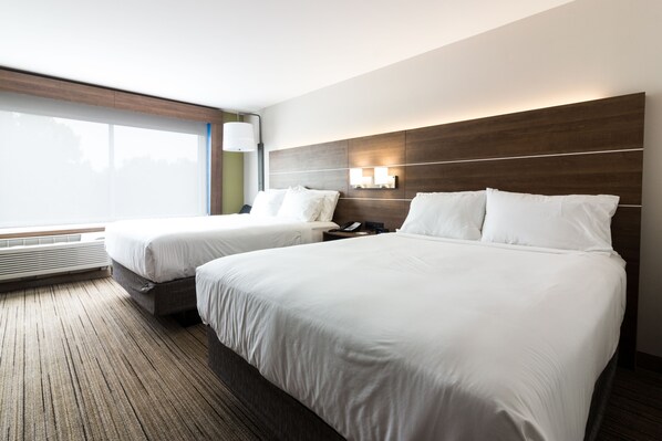 Habitació d'hotel amb dos llits, una finestra gran, una làmpada penjada a la paret i un calefactor incorporat.