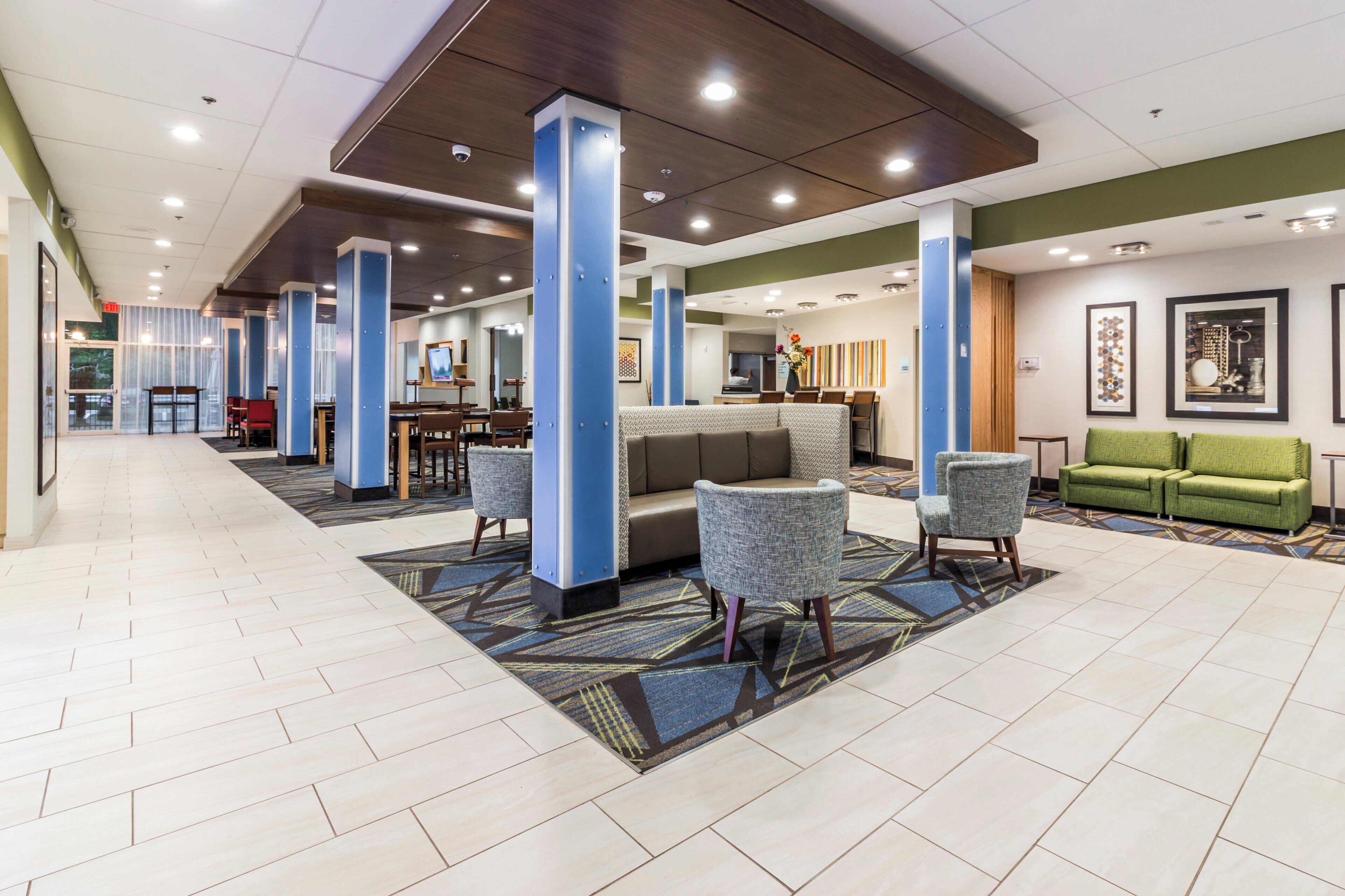 A hotel lobby with a reception desk, seating area, and a green sofa.