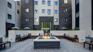 A courtyard with a central fire feature, benches, and umbrellas.