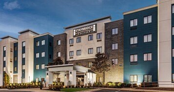 Un hotel Staybridge Suites con una fachada moderna, varios pisos y una zona de entrada cubierta.