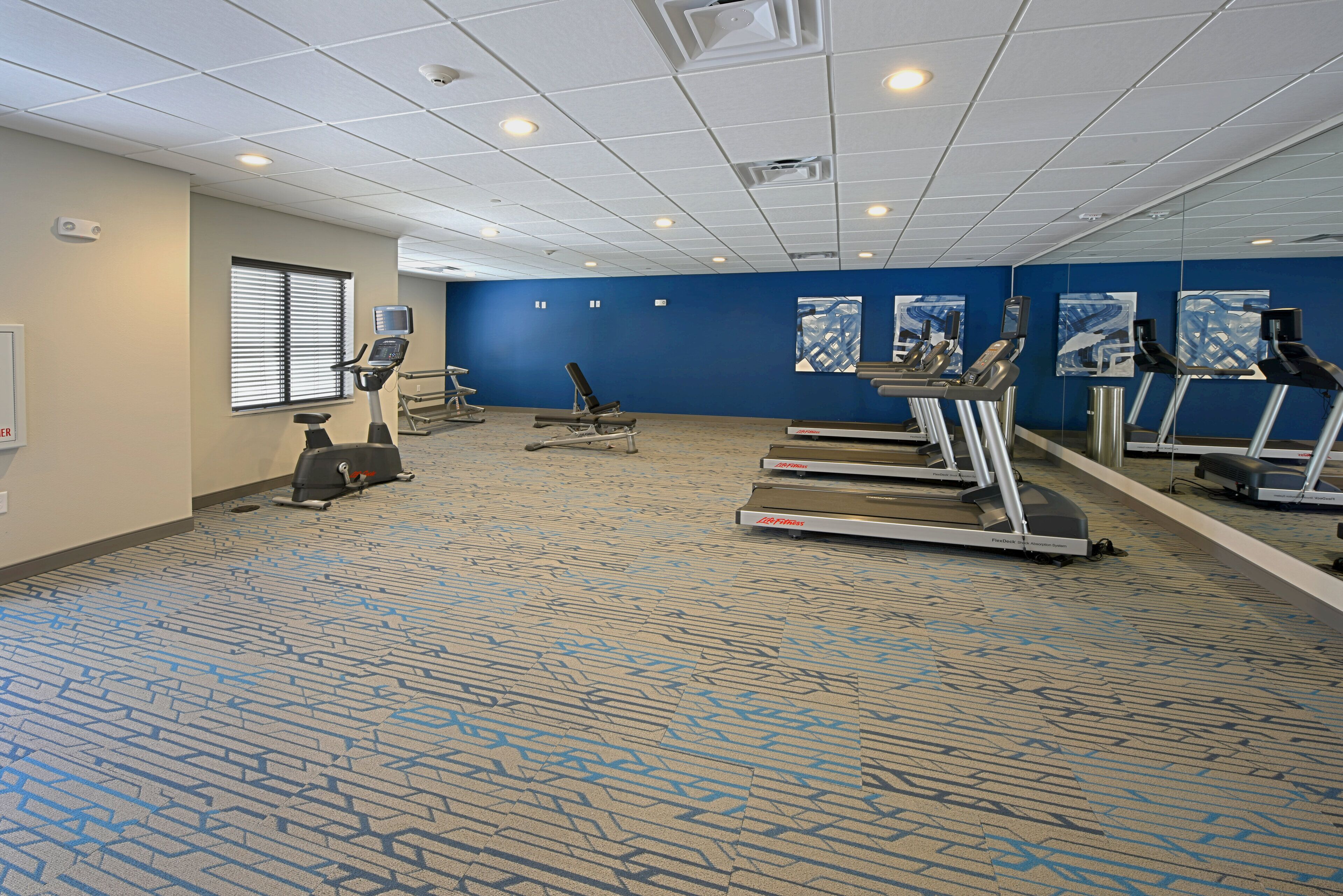 A fitness room with treadmills, a stationary bike, and an elliptical machine.