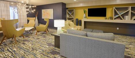 A modern living room with a sofa, chairs, a TV, and a patterned carpet.