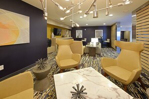 Un hall d’hôtel moderne, doté d’un espace salon, d’une table en marbre et d’une décoration contemporaine.