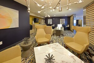 Un moderno vestíbulo de hotel con asientos, una mesa de mármol y decoración contemporánea.