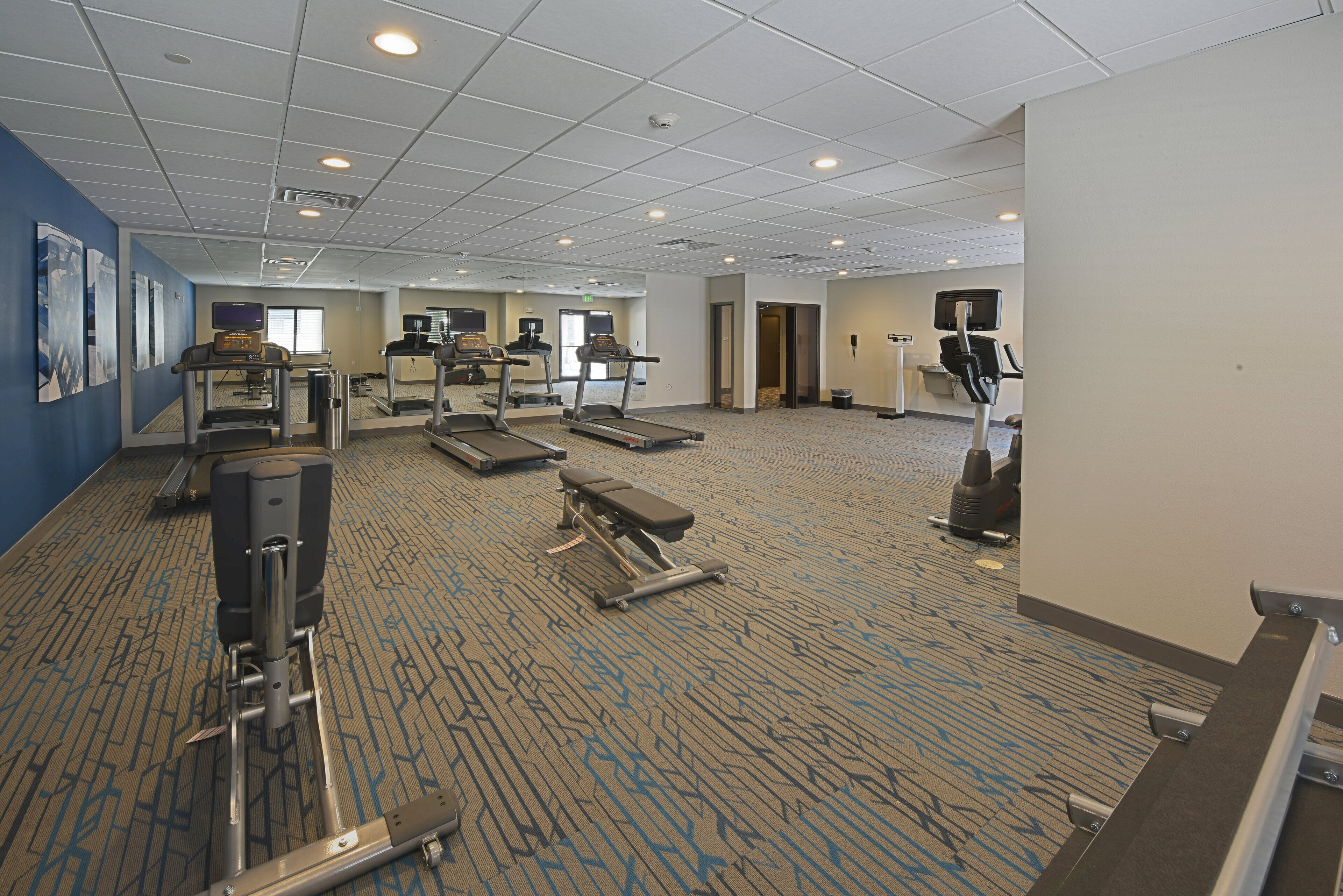 A hotel fitness center with treadmills, elliptical machines, and weight equipment.