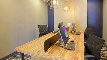 A conference room with a wooden table, black chairs, and a modern pendant light fixture.