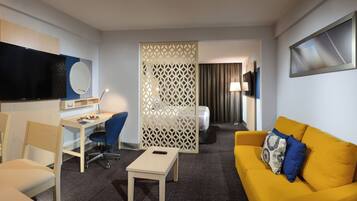 Relax in a stylish room with a flat-screen TV, comfortable sofa, and a bed with a dark curtain.