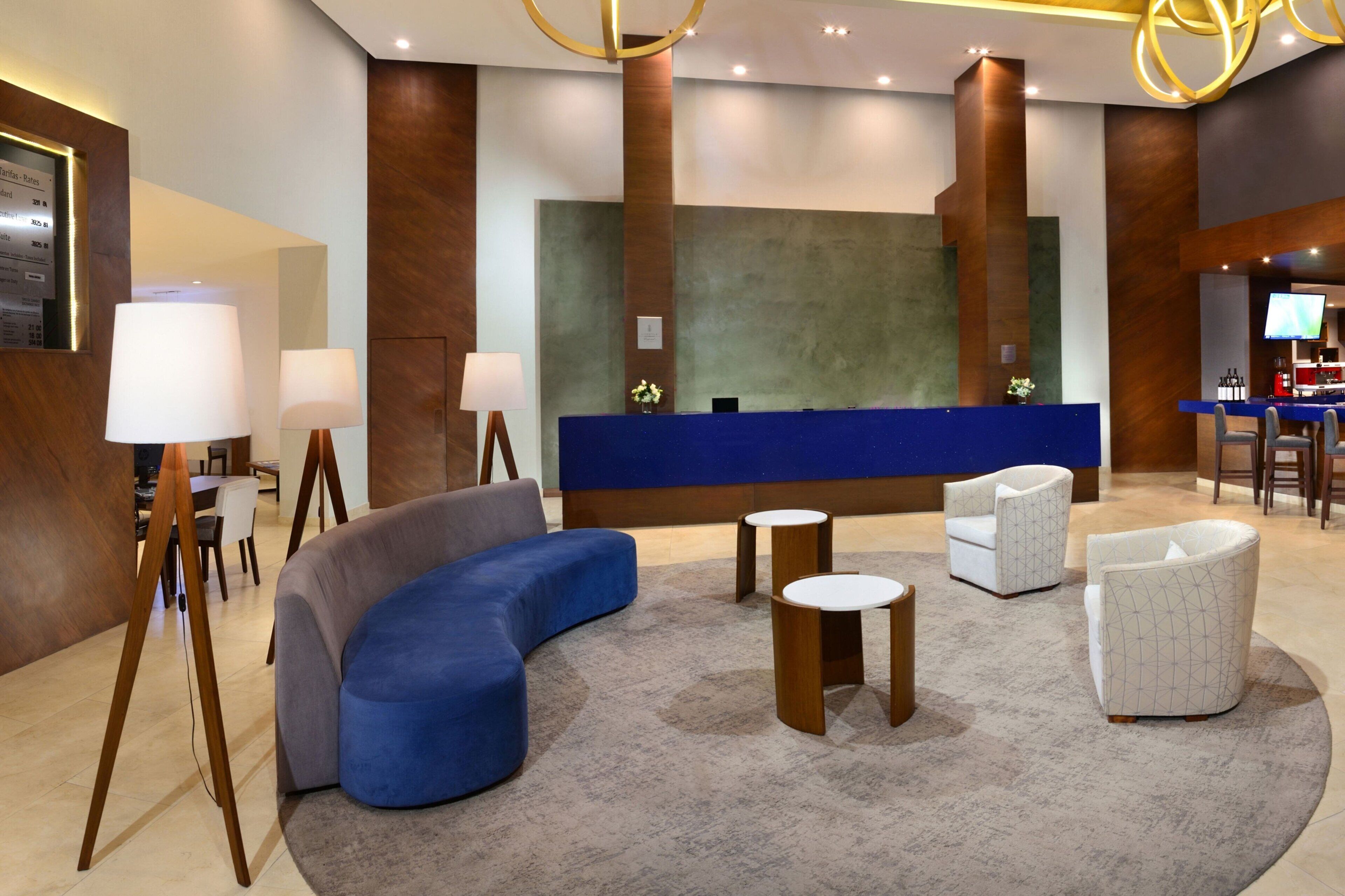 A modern lobby with a reception desk, seating area, and a bar.