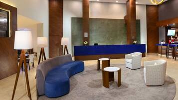 A modern lobby with a reception desk, seating area, and a bar.
