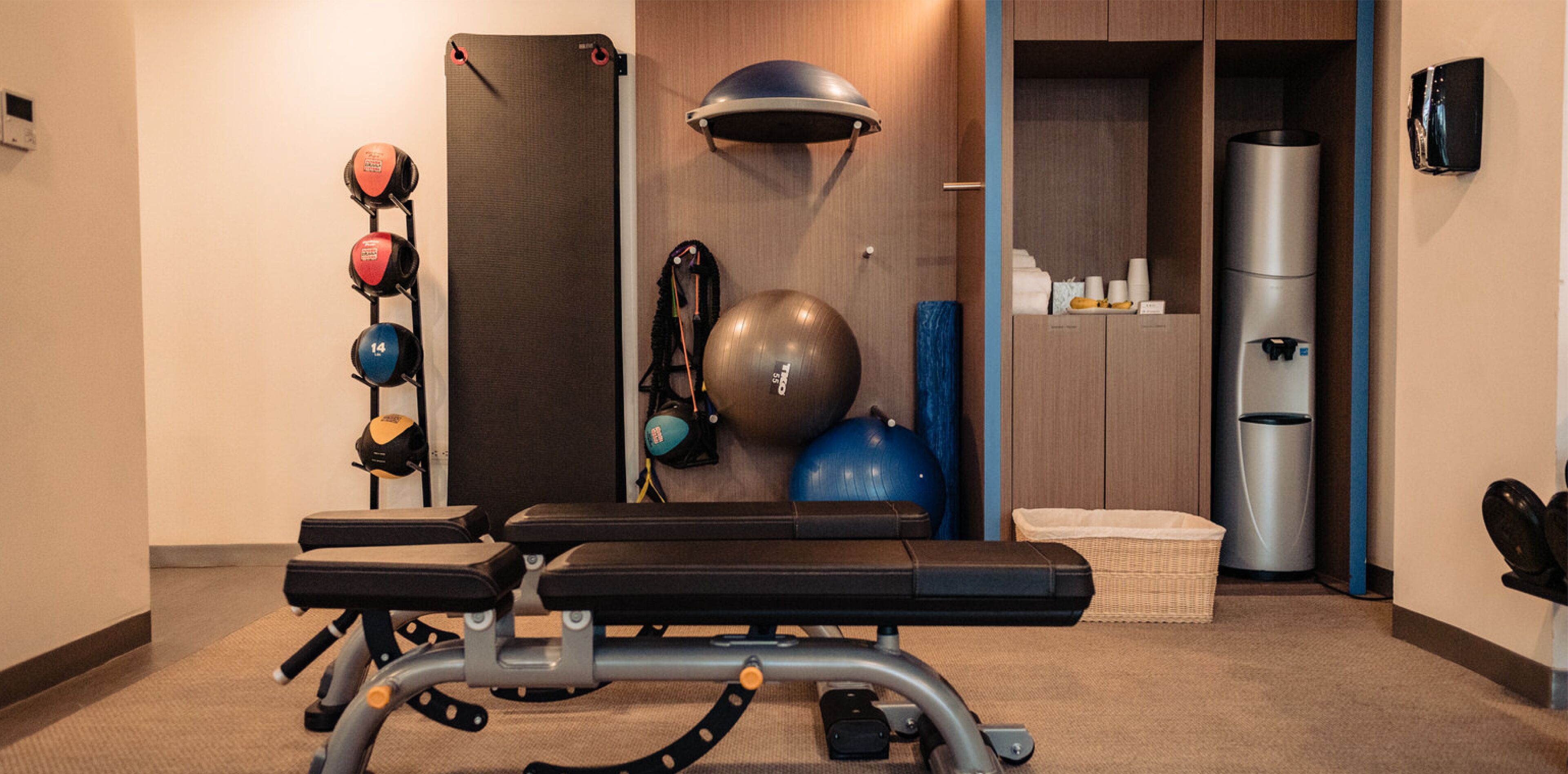 A gym with exercise equipment, a wall-mounted exercise ball, and a water dispenser.