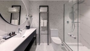 Un baño moderno con un lavabo blanco, espejo y cabina de ducha de vidrio.