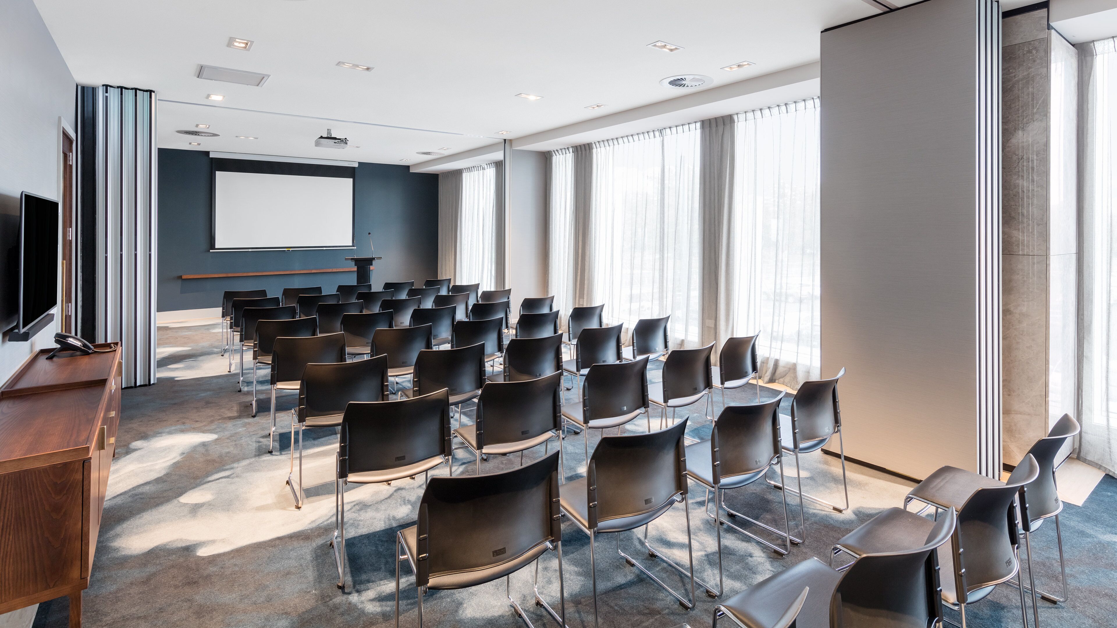 A conference room with rows of chairs, a projector screen, and a podium.