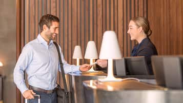 A reception area with a wooden panel background, a reception desk, and two lamps.