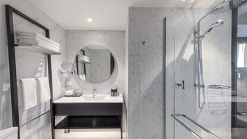 A modern bathroom with a glass shower enclosure, a round mirror, and a black vanity.