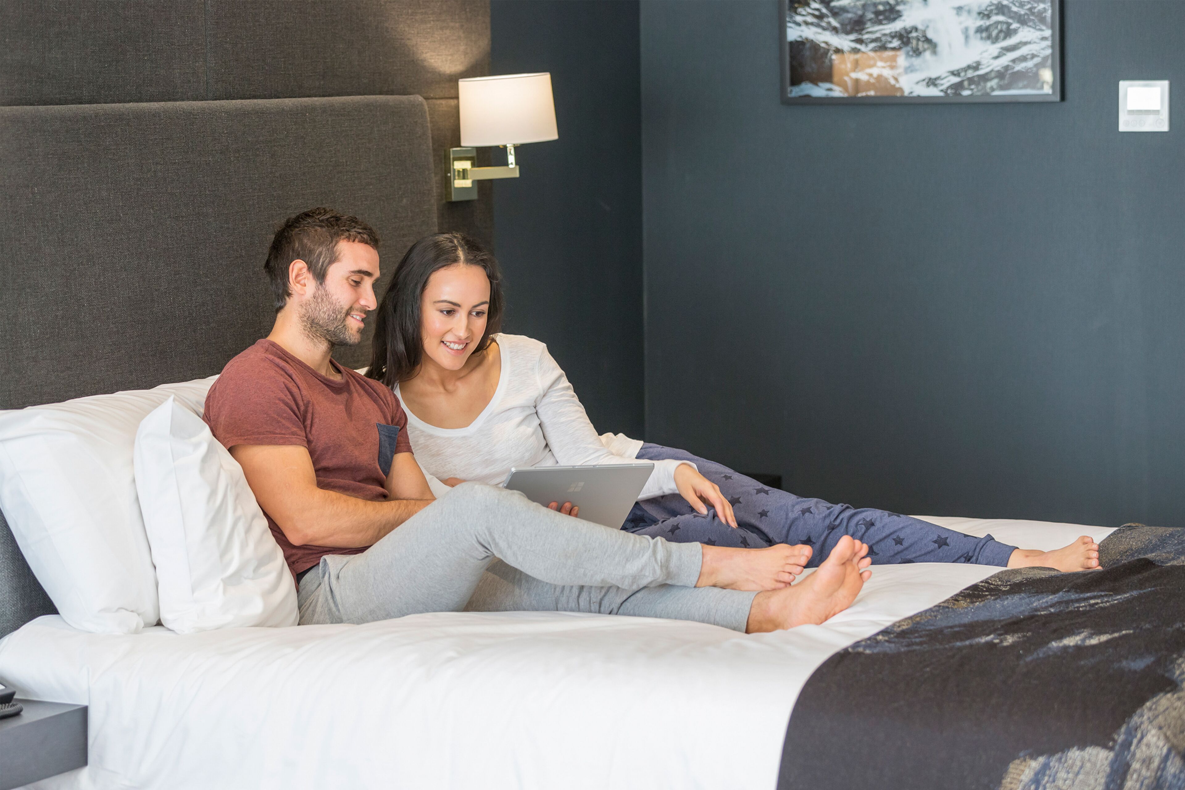 A bedroom with a bed, a nightstand, a lamp, and a painting on the wall.