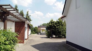 A courtyard with a brick building, a pergola, and a covered area with a white canopy. - La Domus Premium (Lotte)