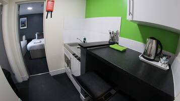A compact kitchen with a black countertop, a green towel, and a kettle.