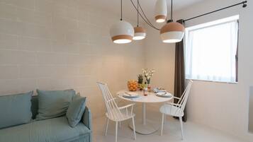 A dining area with a round table, white chairs, and hanging pendant lights.