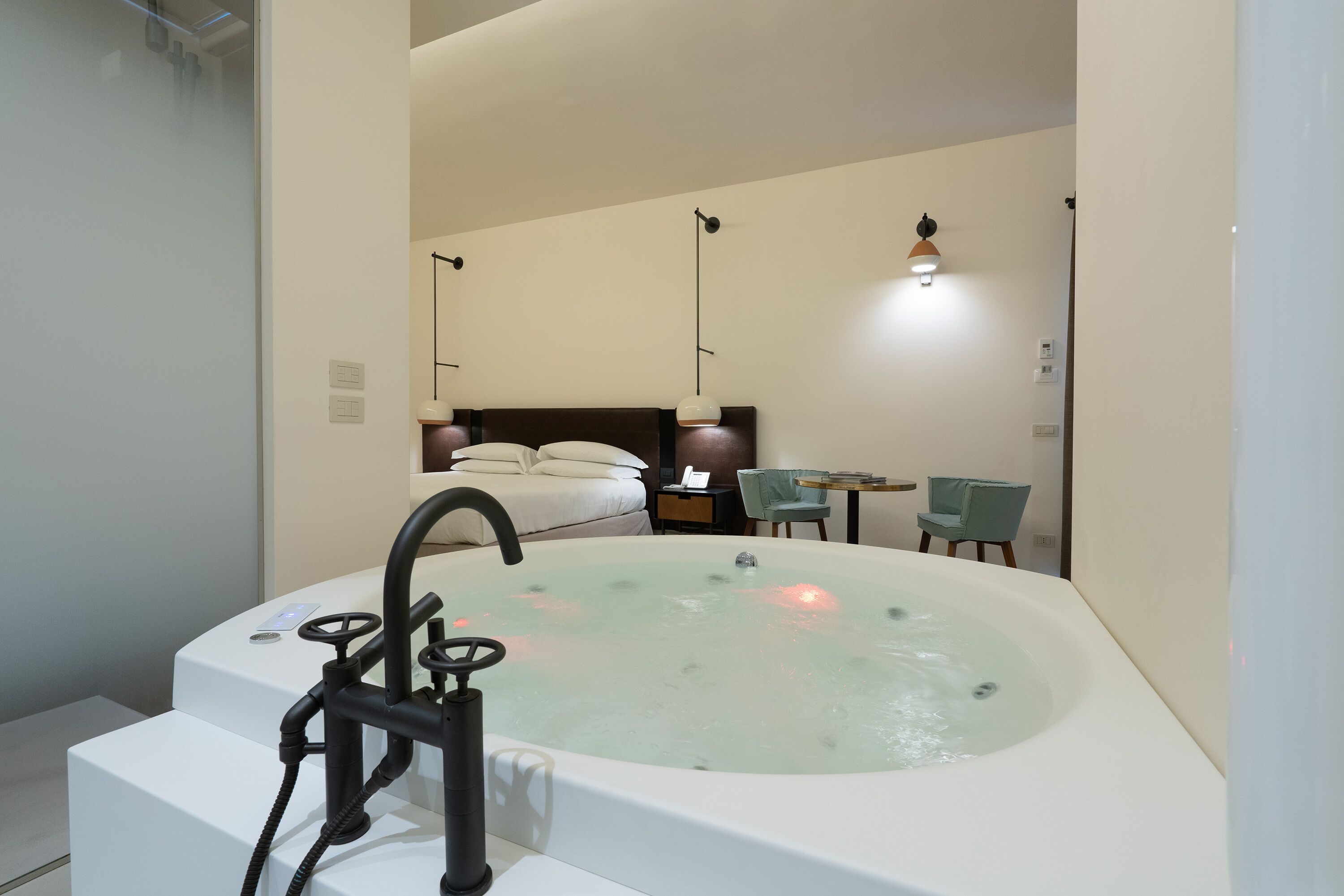 Un baño moderno con una bañera grande, una zona de ducha separada y un pequeño rincón de descanso con una mesa y sillas.