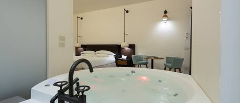 Un baño moderno con una bañera grande, una zona de ducha separada y un pequeño rincón de descanso con una mesa y sillas.