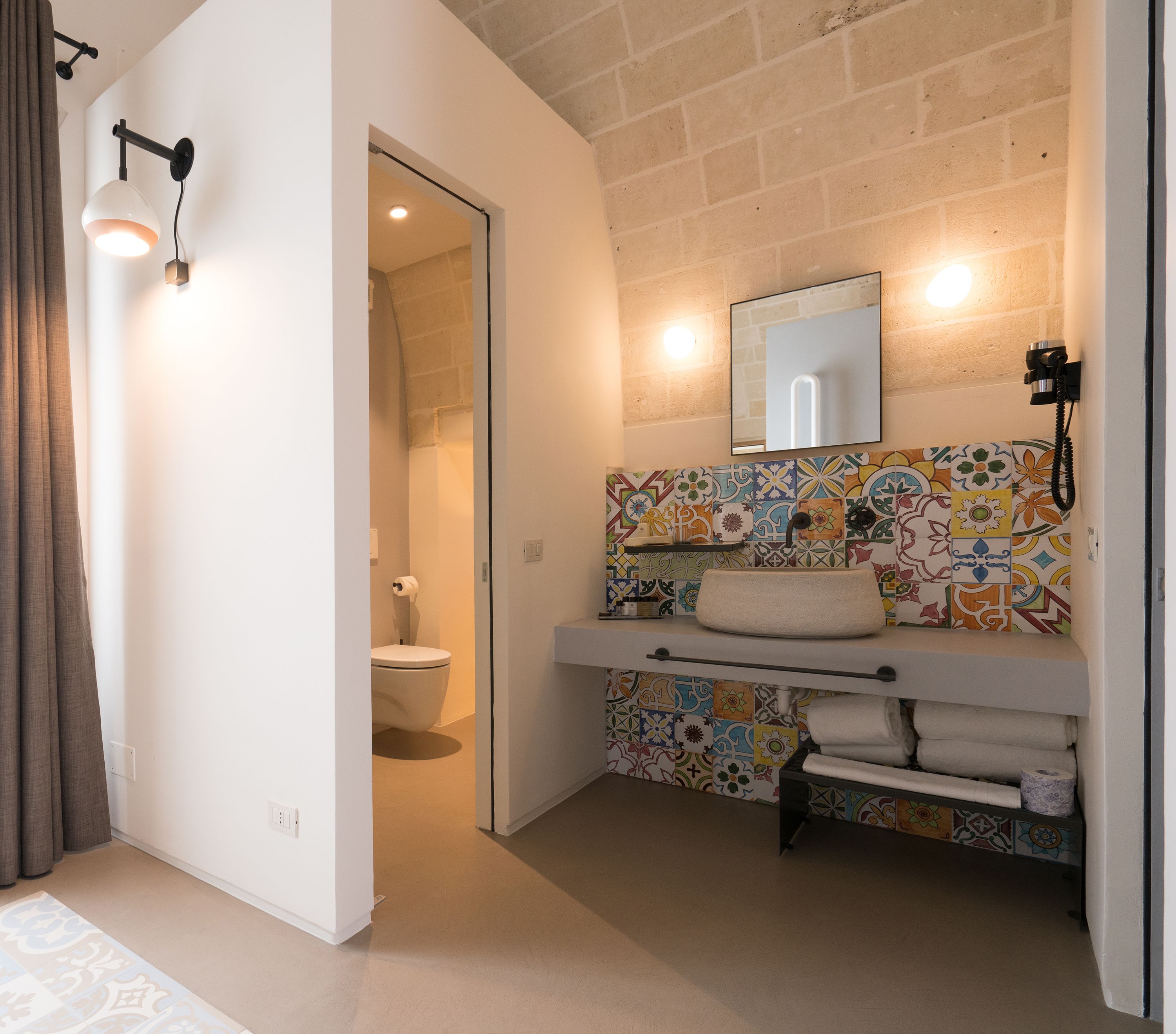 Un baño con salpicadero de azulejos, un lavabo con toallero, un inodoro y una zona de ducha.