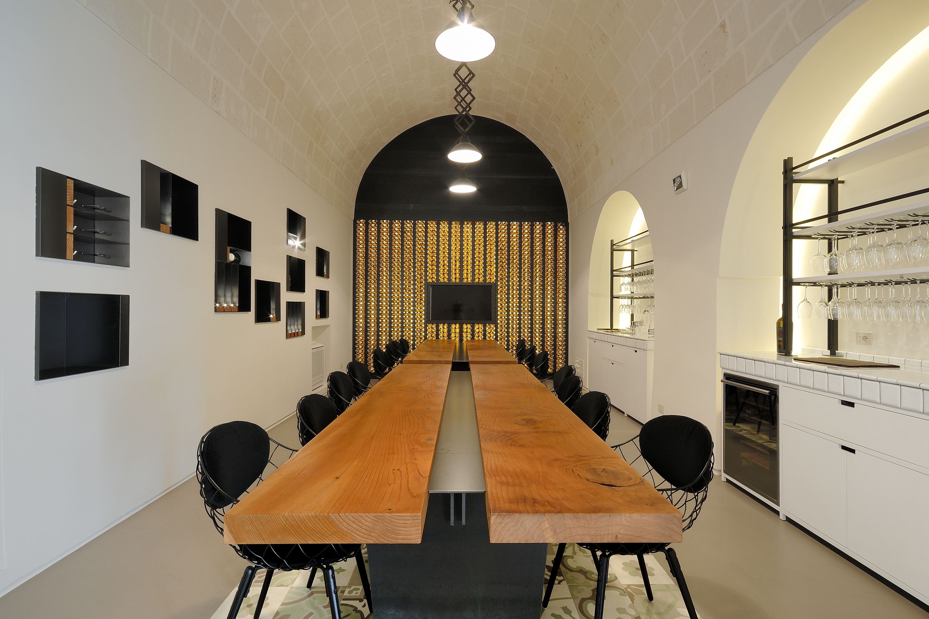 A conference room with a long table, chairs, a projector screen, and a decorative wall.