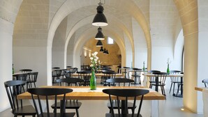 Een ruime eetruimte met hoge gewelfde plafonds en meerdere tafels en stoelen.