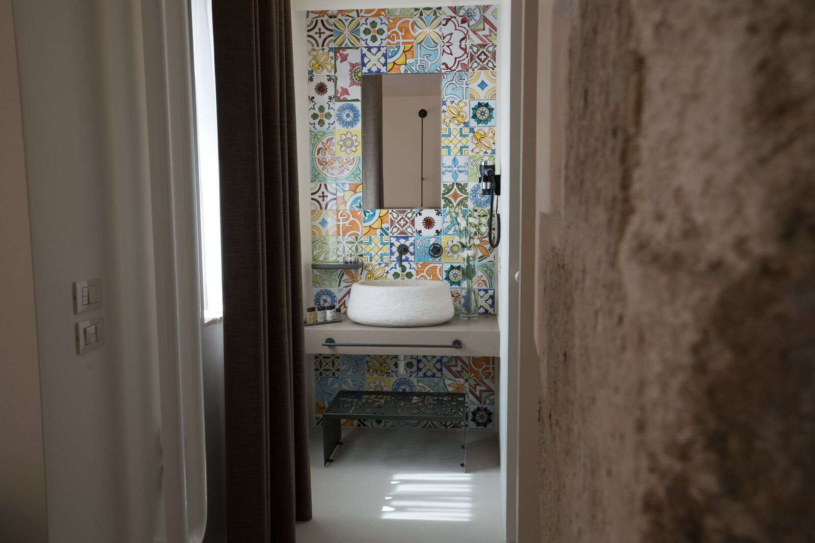 Un baño con salpicadero de azulejos, un lavabo y un espejo.