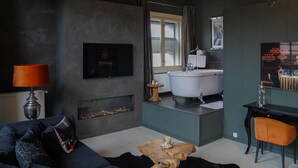 A modern bathroom with a bathtub, a large mirror, and a window. - Hotel Huis van Bewaring (Almelo)