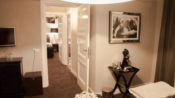 A hotel room with a bed, a bedside table with a lamp, a framed picture on the wall, and a television on the wall.