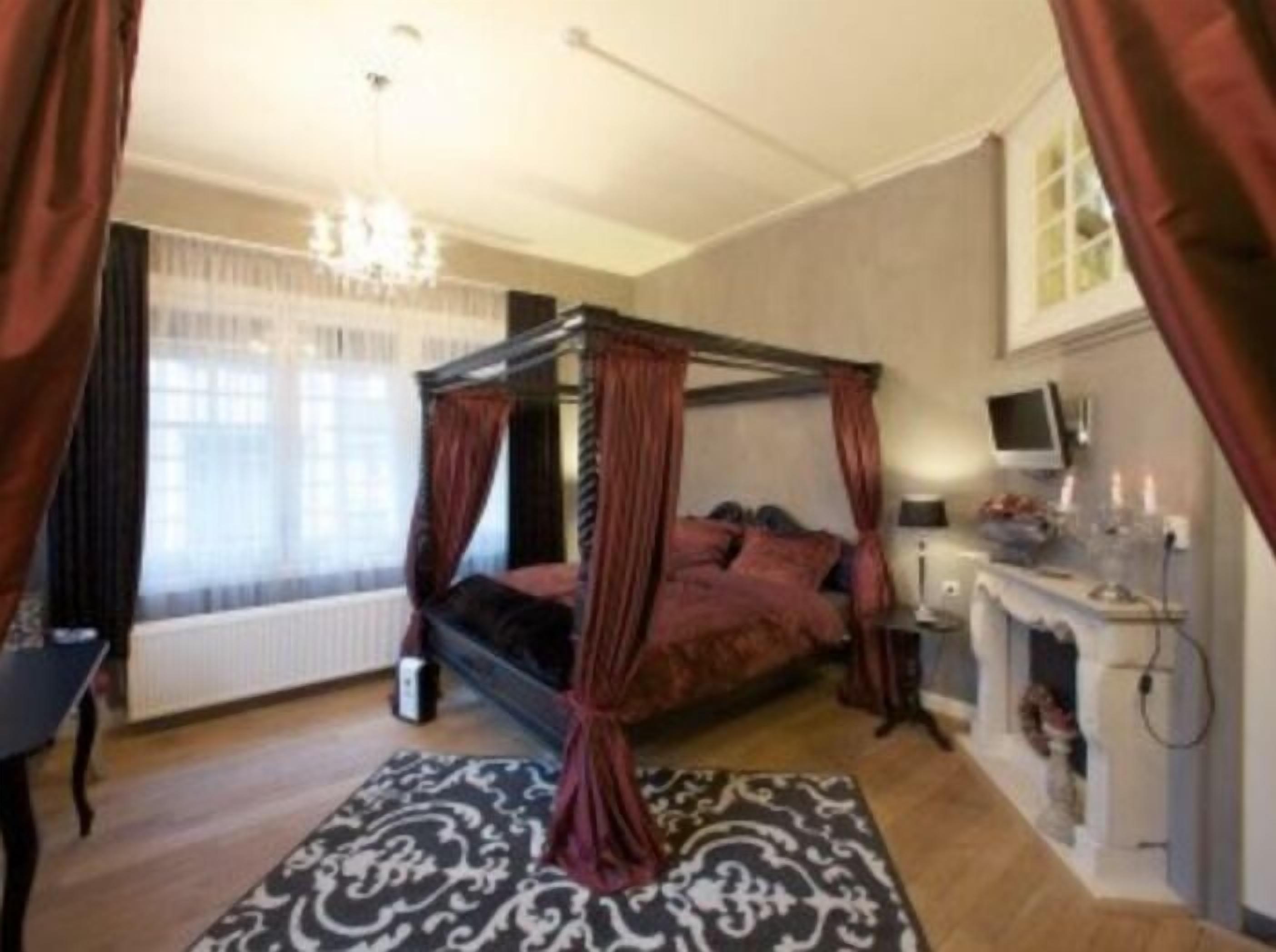 Un dormitorio con cama con dosel, candelabro, televisor y chimenea.