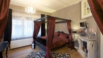 Un dormitorio con cama con dosel, candelabro, televisor y chimenea.