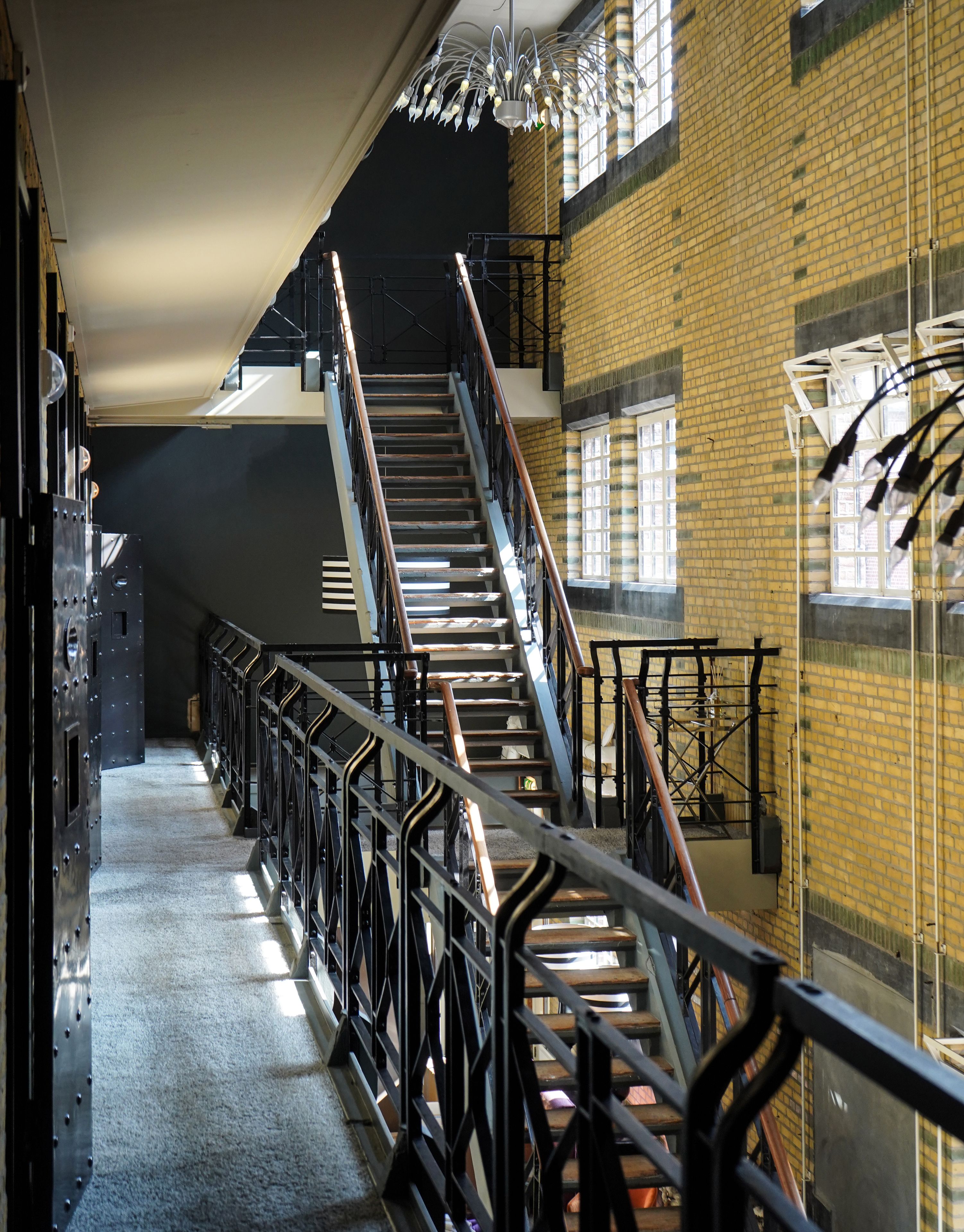 Una escalera en un edificio con barandillas de metal y un muro de ladrillo.