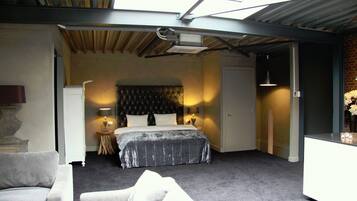 A bedroom with a bed, bedside lamps, a desk, and a chair.