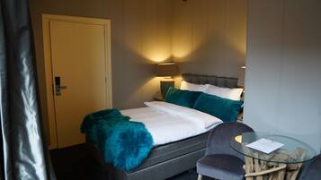 Une chambre d’hôtel avec un lit, une chaise, une table en verre et une lampe.