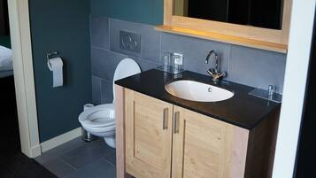 A modern bathroom with a wooden vanity, a white sink, and a mirror above the sink.