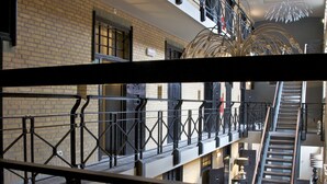 A multi-level interior with a staircase, metal railings, and a chandelier. - Hotel Huis van Bewaring (Almelo)