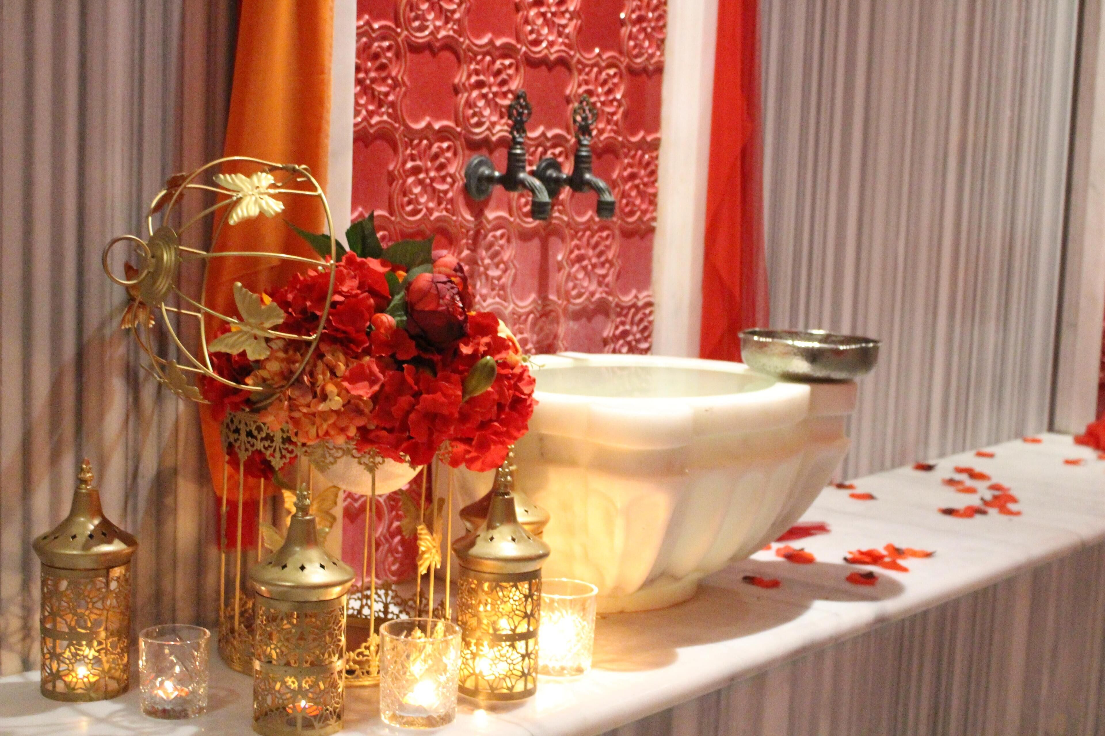 A bathroom with a white sink, decorative candles, and a floral arrangement.