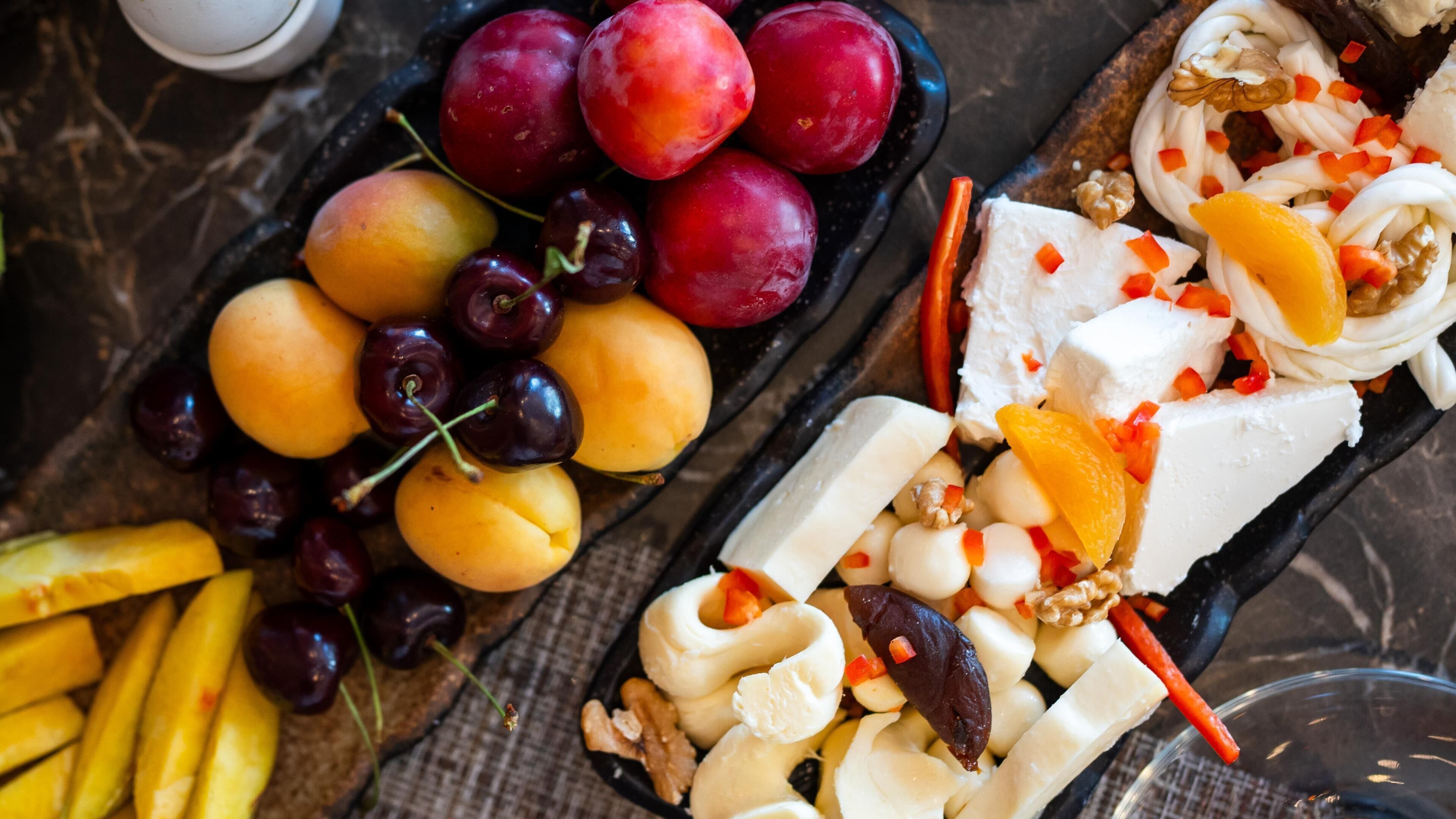 Una tabla de fiambres con varios quesos, frutas y frutos secos.