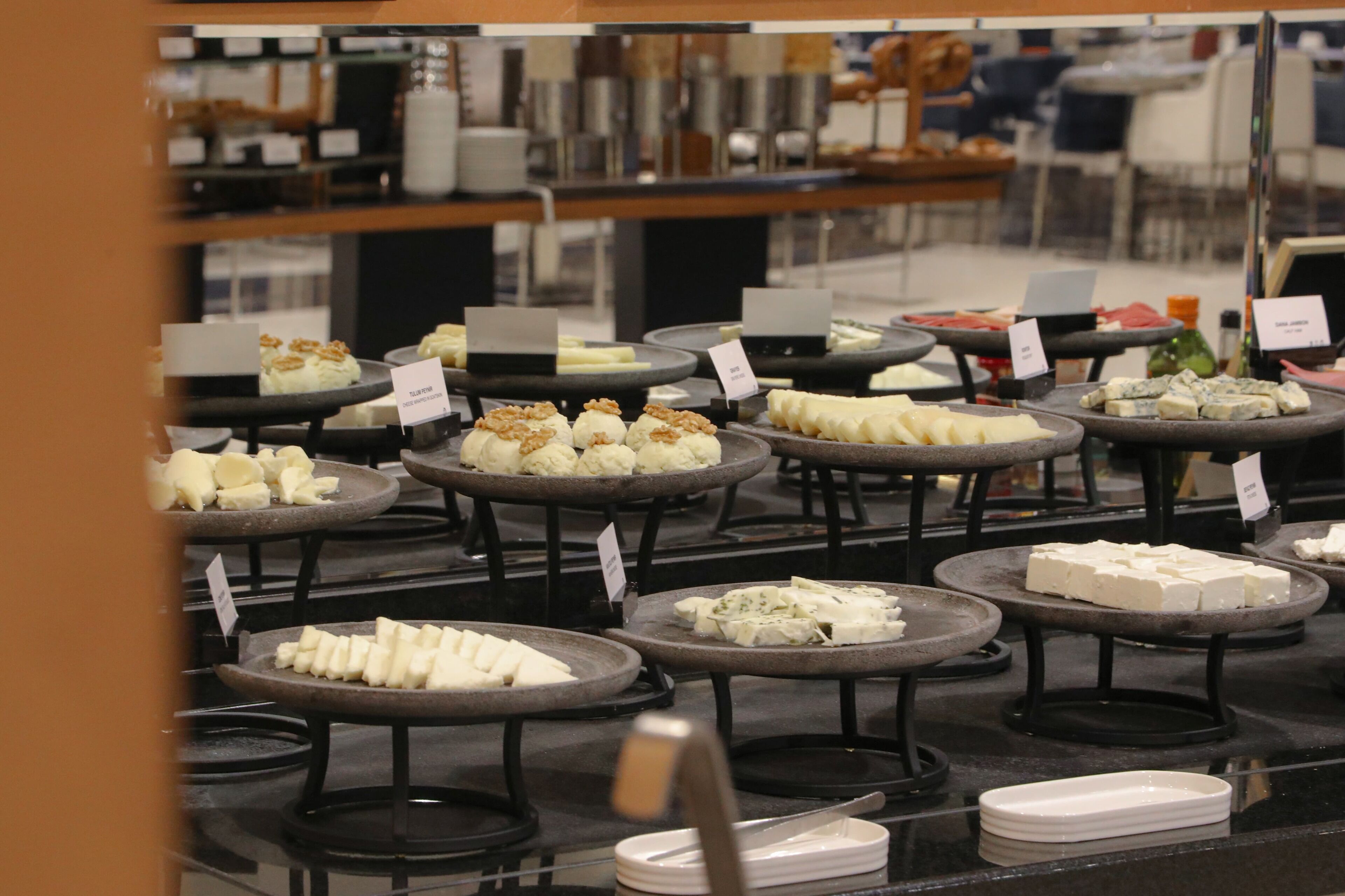 A cheese display with various types of cheese arranged on round tables.