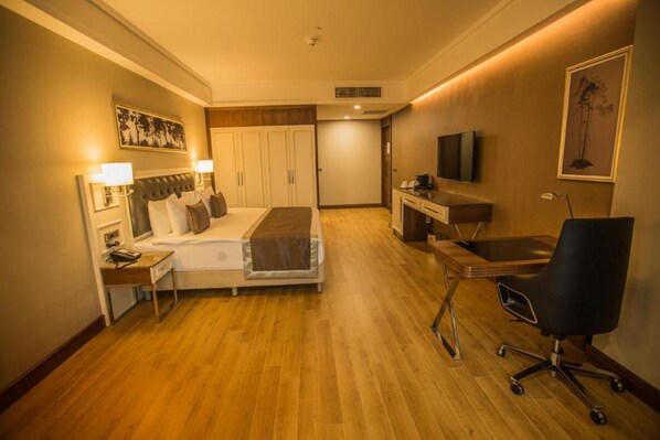 A hotel room with a bed, bedside table, desk, chair, TV, wardrobe, and artwork on the walls. - Radisson Blu Hotel Diyarbakir (Diyarbakir)