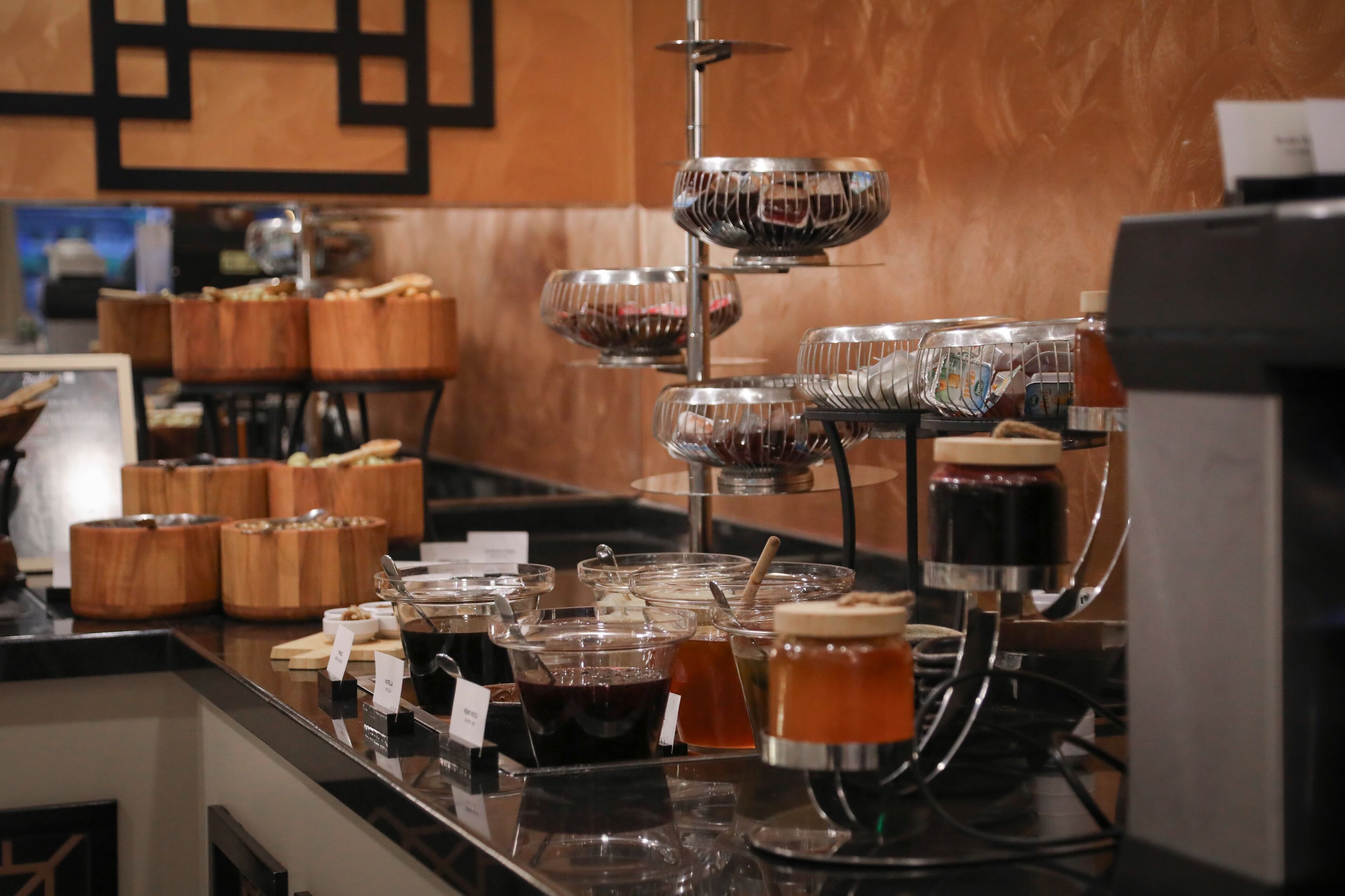 Un espace buffet où sont disposés divers récipients contenant de la nourriture et des boissons, notamment des bocaux et des bols, sur un comptoir.