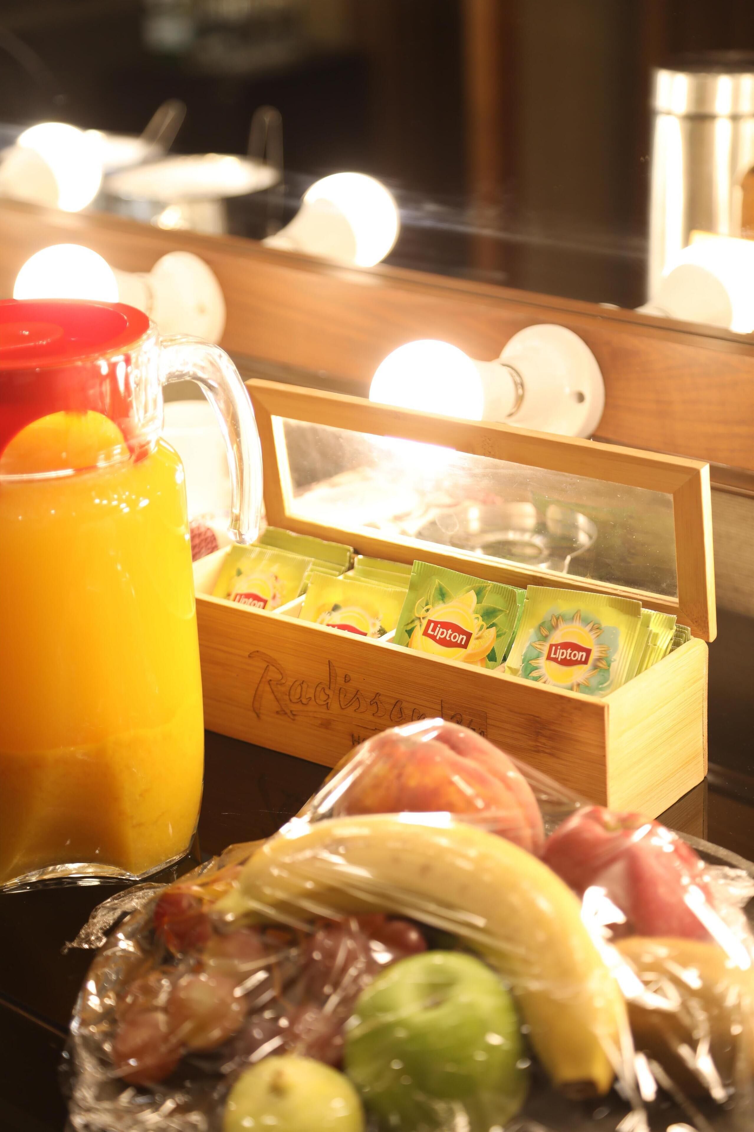 Ein Frühstückstisch mit einer Obstschale, einem Saftkrug und einer Packung Lipton Teebeutel.