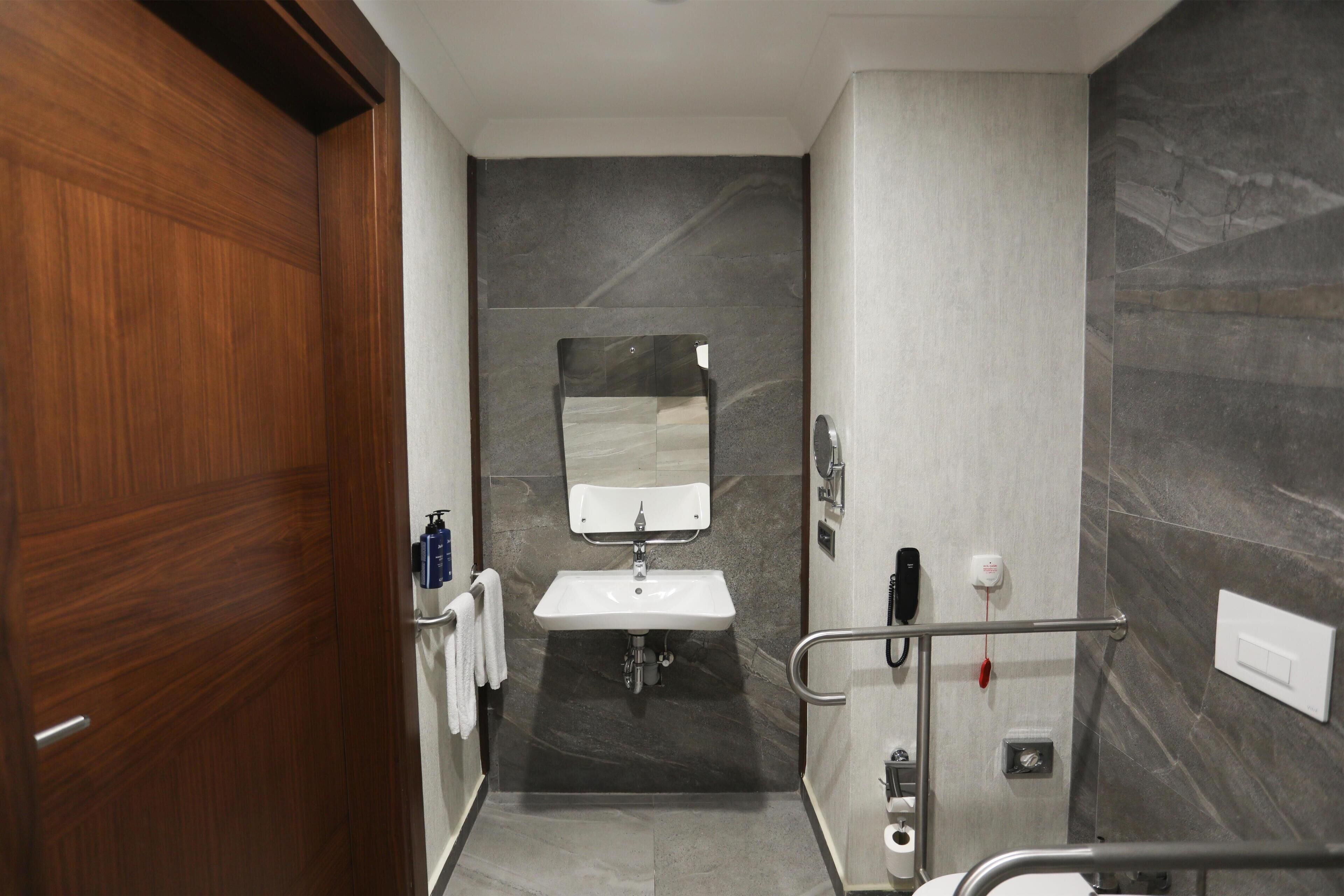 Een moderne badkamer met een houten deur, een wastafel, een spiegel en een douche.