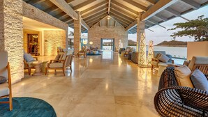 A spacious indoor area with a high ceiling, stone walls, and a view of the sea. - Royalton Bavaro (Punta Cana)